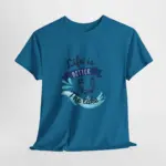 Teal blue short-sleeve t-shirt laid flat showing 'Life is Better at the Lake' graphic with wave splash and sailboat design on front, displayed against light gray background