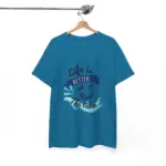 Teal blue short-sleeve t-shirt hanging on wooden hanger from chrome rod, displaying 'Life is Better at the Lake' graphic with wave splash and boat design against white background
