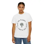 Woman with braided hair pulled back wearing a white short-sleeve crew neck t-shirt featuring a circular design with 'LOVE THE PLANET' text surrounding a tree graphic in dark green, paired with blue jeans against a white background