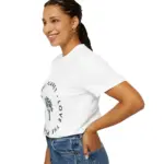 Woman with braided hair smiling while wearing a white short-sleeve t-shirt featuring a circular 'LOVE THE PLANET' text design with a tree graphic, paired with blue jeans, shown from the side against a white background
