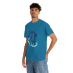Man in casual stance wearing teal blue crew neck t-shirt with 'Life is Better at the Lake' graphic featuring wave and boat design, paired with light wash denim jeans against white background